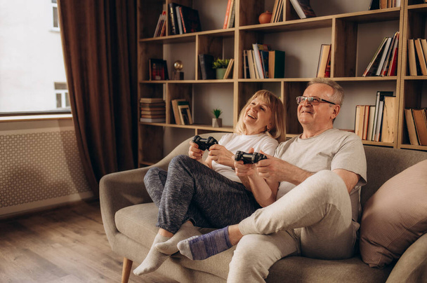 Счастливая старшая белая пара играет дома в игры. - Фото, изображение