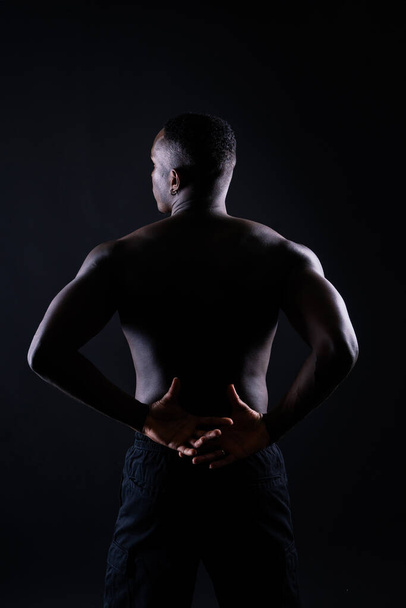 One young african muscular build man standing topless silhouette isolated on a black background - Valokuva, kuva