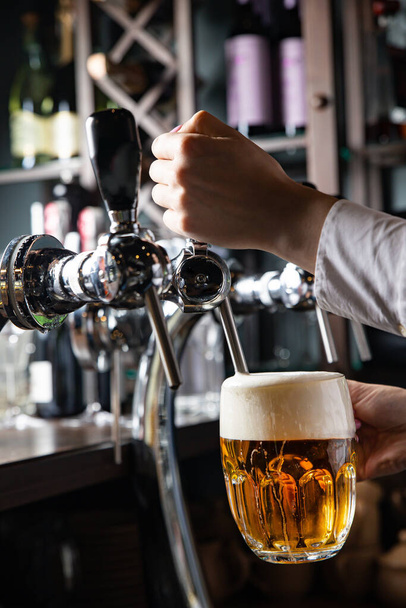 A bartender pours a glass of beer in a bar. - 写真・画像