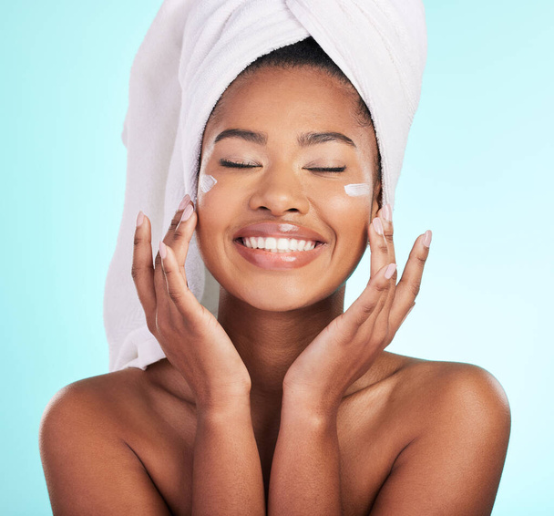Skincare, beauty and lotion, black woman with smile on face for anti aging or skin glow on blue background. Cosmetics, facial and cream, African model with moisturizer or cleansing product in studio - Photo, Image