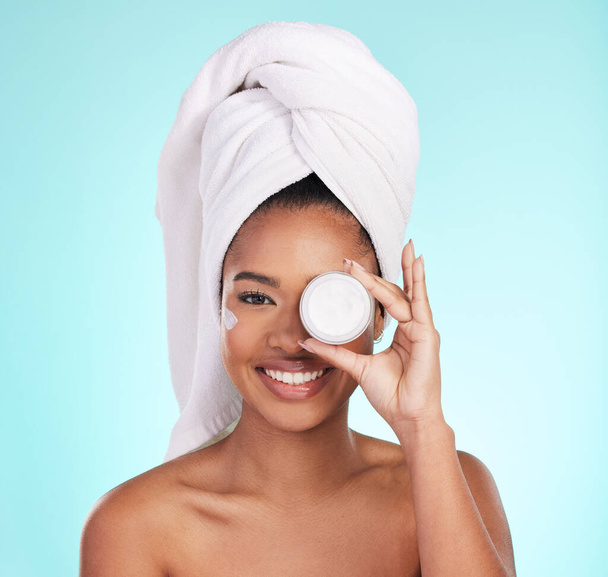 Black woman, jar and skin cream in studio portrait with smile for skincare, wellness or self care by blue background. Girl, african and model with product by eye for natural glow, beauty or cosmetics. - Photo, image