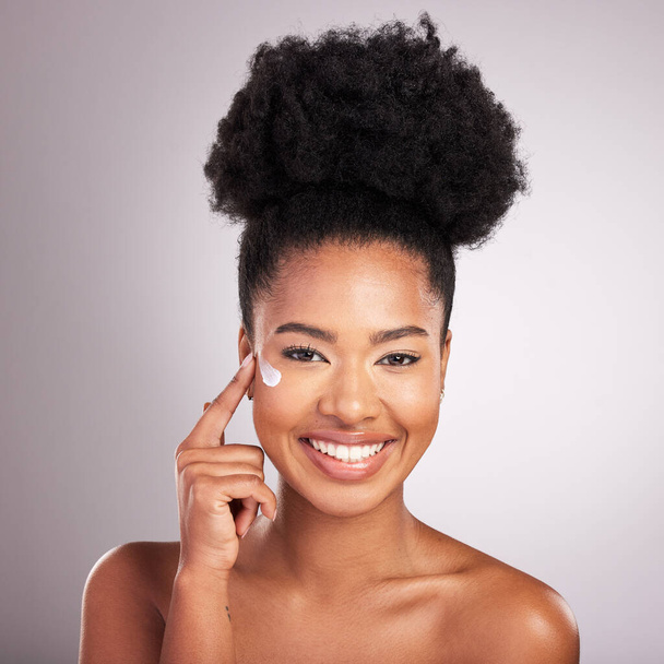 Black woman, face and moisturizer cream for skincare beauty or cosmetics against a gray studio background. Portrait of happy African female with smile for moisturizing creme, lotion or facial product. - Foto, Imagem