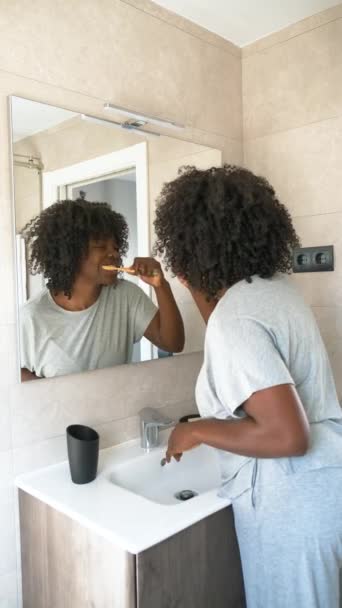 Jeune femme africaine maintenant son hygiène dentaire avec une brosse à dents en bambou. Nettoyage des dents le matin. - Séquence, vidéo