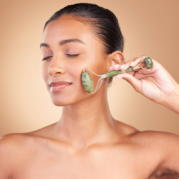 Woman, beauty and derma roller with face, eye closed with facial massage and skincare on studio background. Cosmetic tools, healthy skin glow and female with dermatology, jade quartz and crystal. - Foto, Imagen
