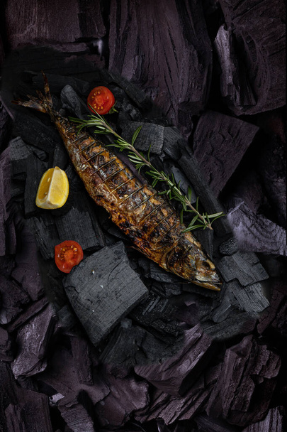 A fish on a grill with a rosemary sprig on it - Valokuva, kuva