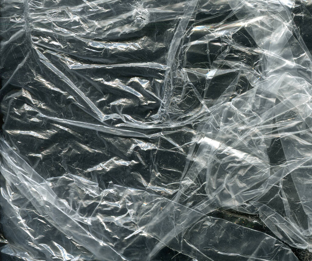 verfrommelde polyethyleen textuur op een donkere achtergrond - Foto, afbeelding
