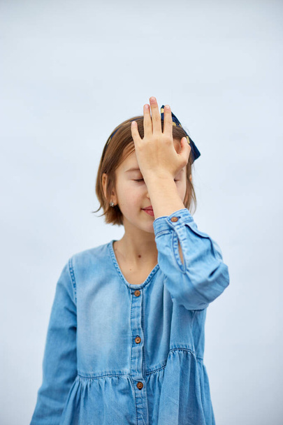 Teen girl child wearing jeans dress put hand on face facepalm in studio on white background, epic fail, amazed with stupid situation - Photo, Image