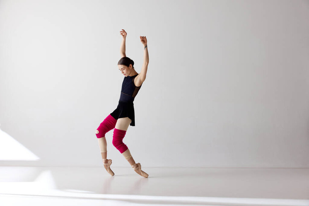 Egy bájos balerina pointe cipőt visel, amely ujjhegyen táncol fehér háttér felett.A művészet, a művész, a mozgás, az akció és a mozgás koncepciója. A kortárs tánc szépsége - Fotó, kép