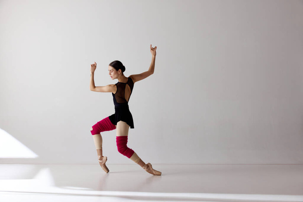 Краса сучасного танцю. Одна молода балерина у взутті танцює на кінчиках пальців на білому тлі. Мистецтво, художник, рух, дія та концепція руху
. - Фото, зображення