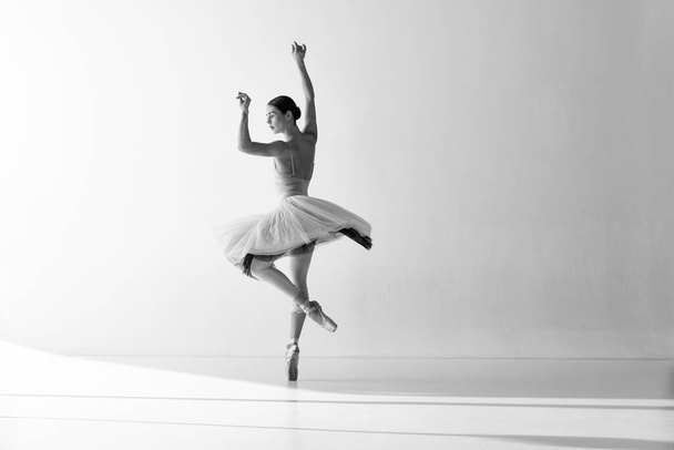 Ballerina im Tutu-Tanz, die Ballettelemente zeigt, während sie auf Spitzenschuhen vor weißem Hintergrund steht. Tänzerin im Ballettkleid. Konzept von Kunst, Schönheit, Streben, Kreativität - Foto, Bild