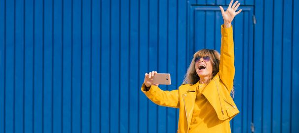 Frau feiert euphorisch mit Handy auf der Straße - Foto, Bild