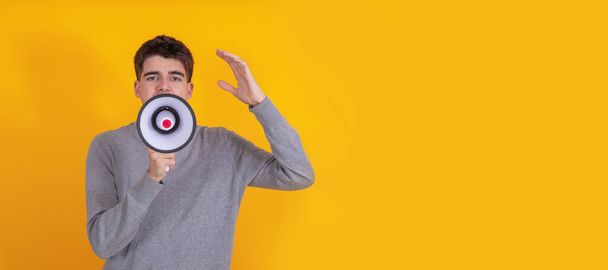 young man isolated on background shouting with megaphone - Foto, imagen