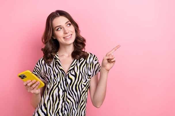 Foto van jong meisje dragen blouse houden samsung telefoon directe vinger kijken lege ruimte snelle internet verbinding geïsoleerd op roze kleur achtergrond. - Foto, afbeelding