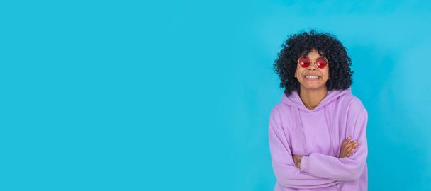 дівчина афро ізольована на кольоровому фоні в сонцезахисних окулярах і фіолетовому пуловері
 - Фото, зображення