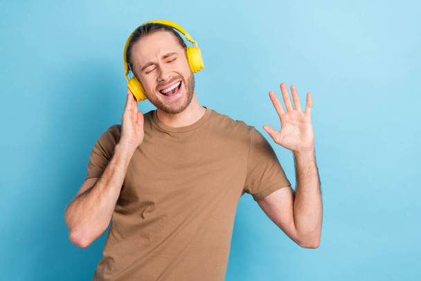 Photo of funny funky man wear beige t-shirt earphones listening songs singing isolated blue color background. - Foto, Imagem