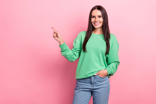 Photo of satisfied woman with straight hairdo dressed green sweatshirt directing at empty space sale isolated on pink color background. - Foto, Imagem