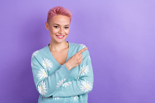 Photo of toothy beaming cheerful woman short hairstyle dressed blue cardigan directing empty space isolated on purple color background. - Fotografie, Obrázek