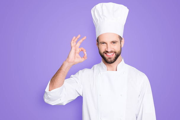 Portrait of cheerful joyful chef cook in beret and white outfit with stubble looking at camera showing ok sign, approve, advice menu isolated on grey background. - Foto, Bild