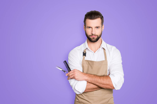Portrait with copy space, empty place of virile harsh barber having his arms crossed, holding equipments in hand, looking at camera, isolated on grey background. - Foto, imagen
