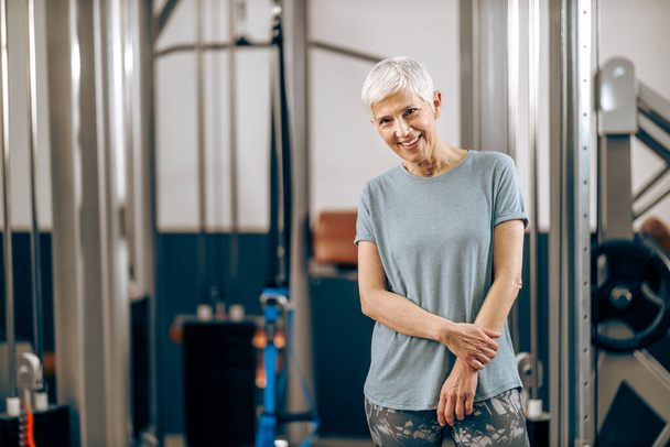 Smiling senior woman is posing after workout in the gym. - Foto, immagini