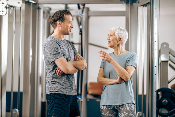 A senior mother and her middle age son talking before have a workout in a gym. - Fotografie, Obrázek