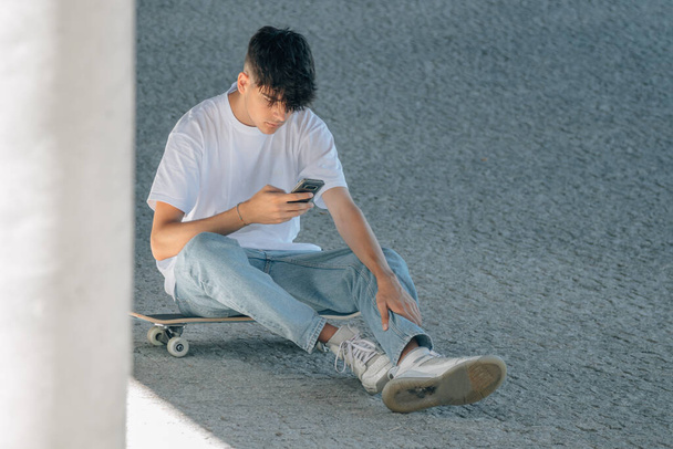 teen boy with skateboard and mobile phone - 写真・画像