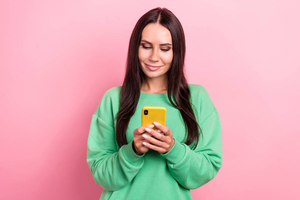 Photo of young youtube blogger attractive hispanic girl wear green jumper hold samsung phone reading last post isolated on pink color background. - Fotoğraf, Görsel
