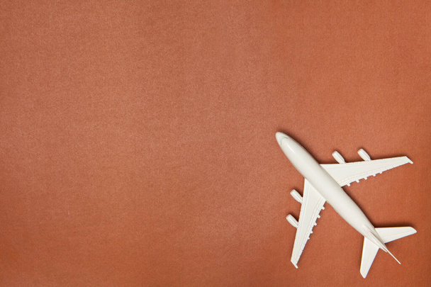 Airplane model. White plane on brown background. Travel vacation concept. Summer background. Flat lay, top view, copy space. - Photo, image