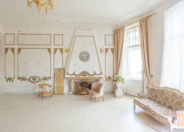 luxuriöse teure Innenausstattung eines großen barocken königlichen Wohnzimmers. antike Möbel, Goldbesatz, riesige Fenster, Kamin mit goldenem Stuck an den Wänden. voller Tageslicht - Foto, Bild