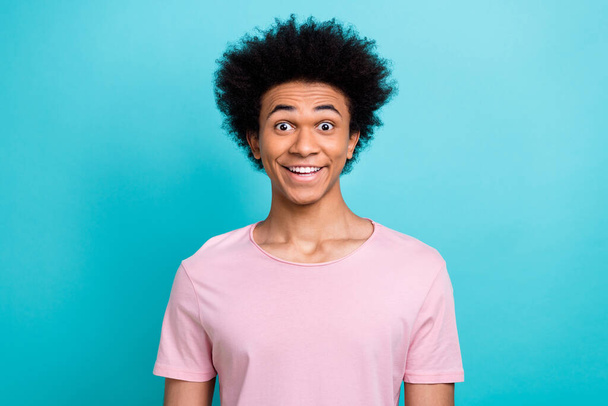 Портрет здивованого смішного похмурого чоловіка, який посміхається носить рожеву футболку цікава брошура після перукарського стиліста ізольовано на синьому кольорі
. - Фото, зображення