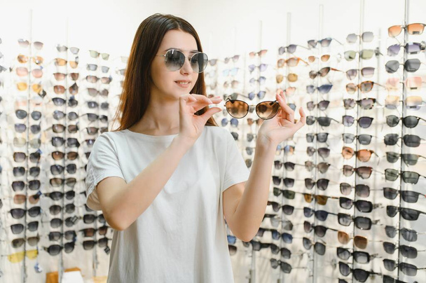 Front view of optician holding sunglasses pairs. - Foto, afbeelding