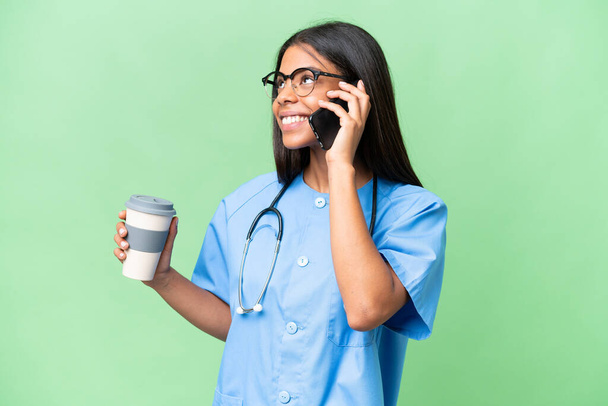 若いアフリカ系アメリカ人看護師の女性が隔離された背景にコーヒーを取り上げ、携帯電話を持って - 写真・画像