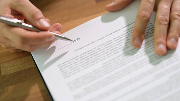 Egy üzletember tollal aláírja a szerződést az asztalnál. Fontos dokumentumok hivatalos hitelesítése koncepció - Fotó, kép