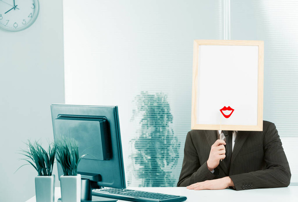 Mężczyzna z oprawioną głowicą znaku w biurze, umieszcza również kobiecy kształt wargi z czerwoną szminką przed dostępną białą przestrzenią. - Zdjęcie, obraz