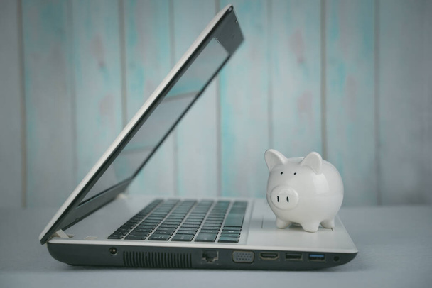 Piggy bank and laptop on table. Concept business finance technology, savings, e-commerce, e-business, deposit or shopping online, wealth from investment, rich profit income, earning, online banking. - 写真・画像