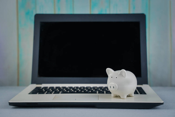 Piggy bank and laptop on table. Concept business finance technology, savings, e-commerce, e-business, deposit or shopping online, wealth from investment, rich profit income, earning, online banking. - Fotó, kép