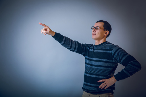 europäisch aussehender Mann mit Brille zeigt die Hand nach vorne auf einem grauen - Foto, Bild