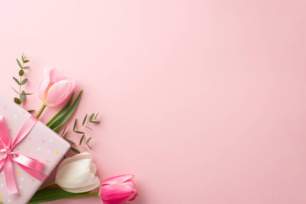 Mother's Day concept. Top view photo of stylish pink giftbox with ribbon bow and bouquet of tulips on isolated pastel pink background with copyspace - Photo, image
