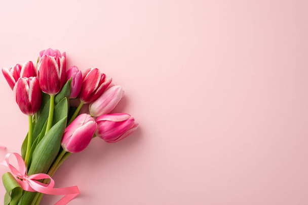 Concept de fête des mères. Photo de vue du dessus du bouquet de tulipes roses attachées avec ruban sur fond rose pastel isolé avec copyspace - Photo, image