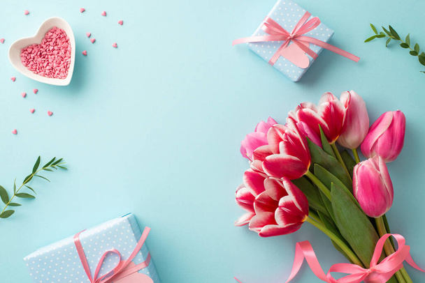 Concepto de celebración del Día de la Madre. Vista superior de la foto del ramo de tulipanes cajas de regalo con arcos y platillo en forma de corazón con aspersiones sobre fondo azul pastel aislado con espacio vacío - Foto, imagen
