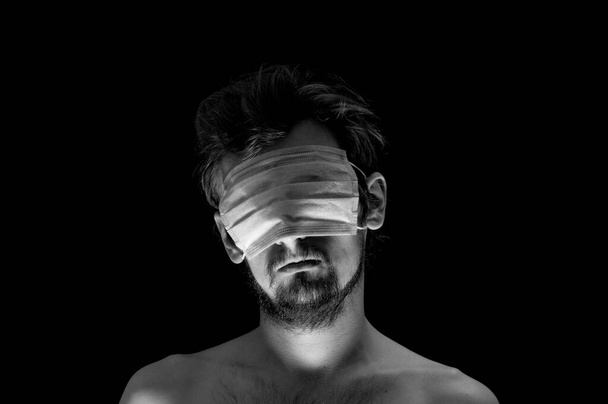 retrato de um cara em um fundo preto, uma máscara em seus olhos - Foto, Imagem