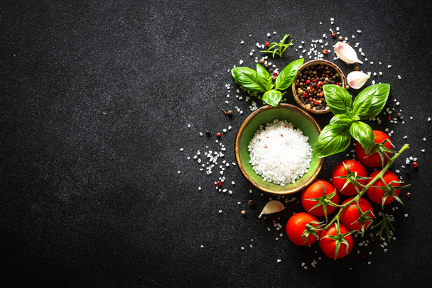 Voedselachtergrond op zwarte stenen tafel met groenten, kruiden en specerijen. Bovenaanzicht met kopieerruimte. - Foto, afbeelding