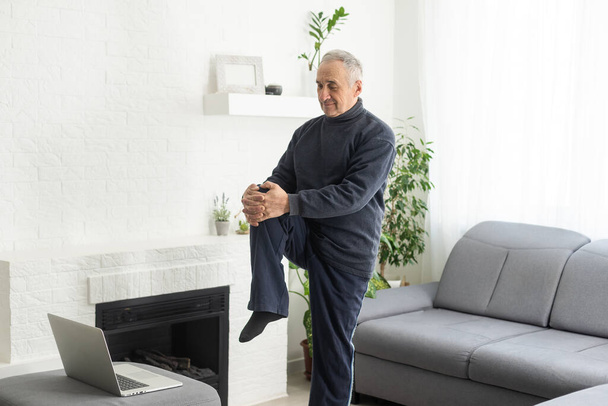 Online workout. elderly man doing exercise with online tutorial at home, panorama, free space. - Foto, Imagen