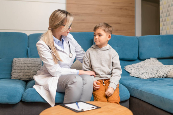 Ο παιδίατρος εξετάζει ένα άρρωστο παιδί. Άρρωστο αγόρι στην κλινική. Παιδική κατ 'οίκον θεραπεία του ιού. - Φωτογραφία, εικόνα