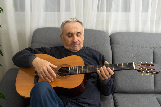 Oudere man speelt thuis gitaar. - Foto, afbeelding