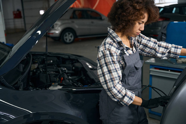 Curly multiracial auto repairman checks car air conditioner, woman uses car air conditioning flush system - Zdjęcie, obraz