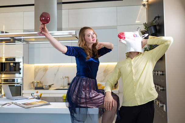 Funny dancing of unicorn at white kitchen. Couple having fun preparing a romantic dinner, listening to music in the modern kitchen. - Фото, зображення