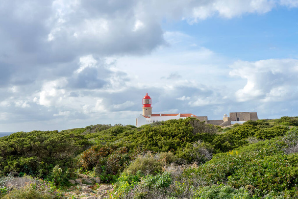 SAGRES, PORTUGAL - FEBRUARY 27, 2023: Lighthouse of Cabo de So Vicente. View of idyllic nature landscape with rocky cliff shore and waves crashing on.  Sagres, Portugal on February 27, 2023 - Photo, Image