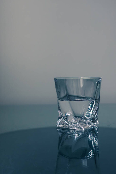 Simple drinking water without gas. Formula water is H2O. The glass is half full or empty. Clear liquid. Water requirement. Clean water in a non-standard glass. - Photo, Image