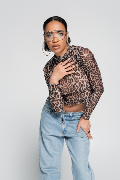 stylish african american model in crop top with animal print and trendy sunglasses posing isolated on grey  - Foto, immagini